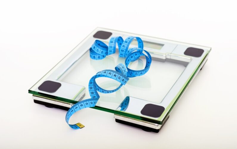 blue-tape-measuring-on-clear-glass-square-weighing-scale-53404